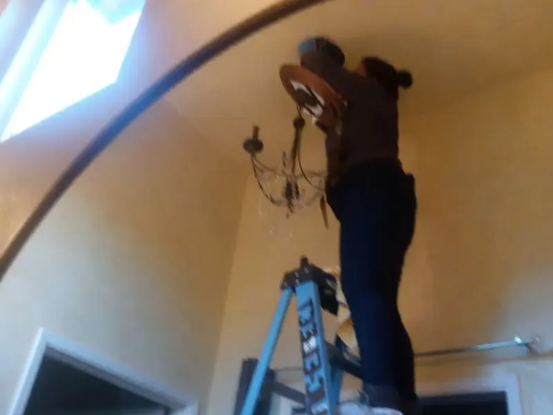 Electrician installing a chandelier in a Chicago Heights residence